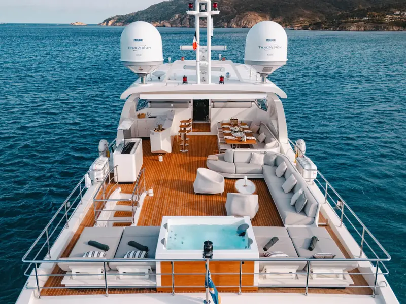 NEMESIS yacht flybridge with teak decking, jacuzzi, lounge seating, and TracVision satellite domes.