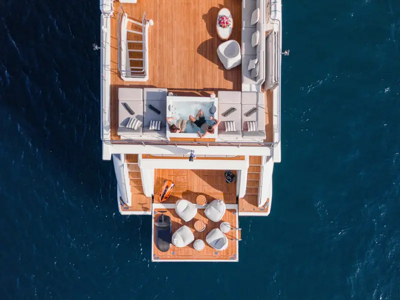NEMESIS yacht aerial view of the flybridge jacuzzi and lowered swim platform with water toys.