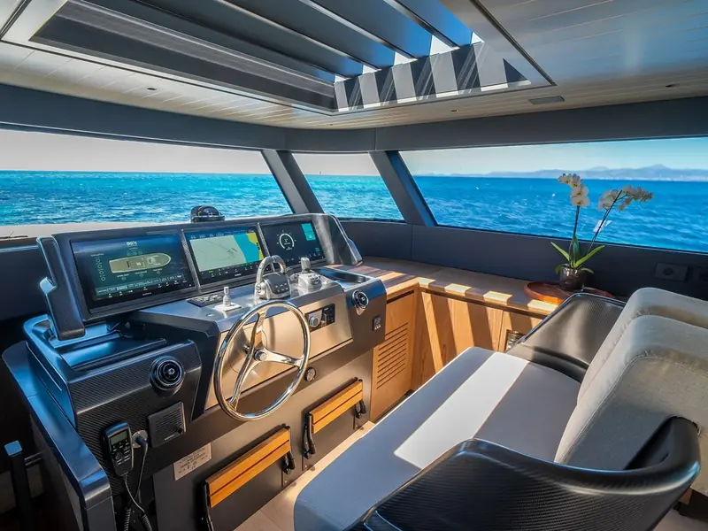 PETITCHET II helm station featuring three Garmin displays, stainless steel steering wheel, and throttle controls.