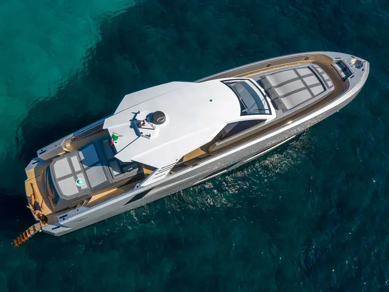 Aerial view of the yacht NEXT at anchor in clear blue water, showing the hardtop, sunpads, and swim platform.