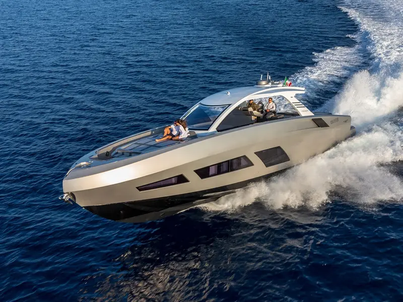 Aerial port side view of yacht NEXT cruising at high speed on blue water with people on the foredeck.