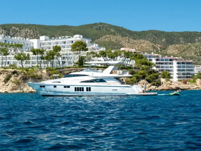 PAPAMARES motor yacht at anchor near a coastal resort with a swim platform deployed.