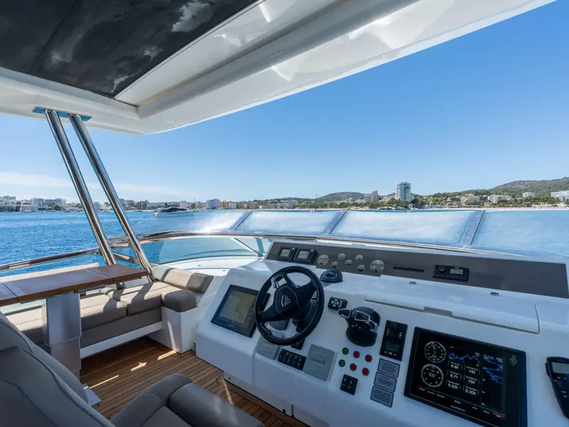 PAPAMARES flybridge helm station with Garmin displays, steering wheel, and throttle controls overlooking a bay.
