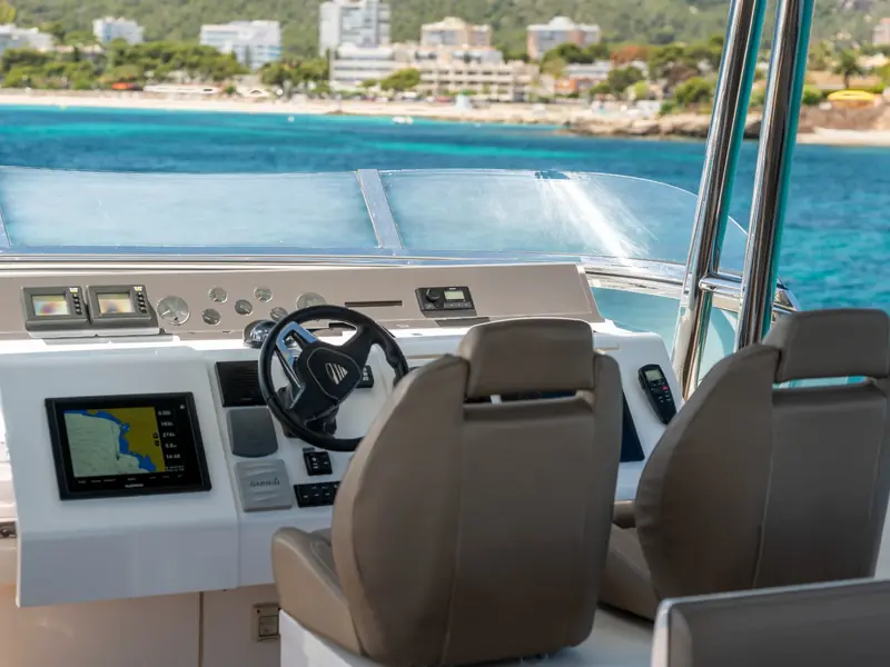 PAPAMARES flybridge helm station with Garmin chartplotter, steering wheel, and leather pilot seats overlooking the sea.