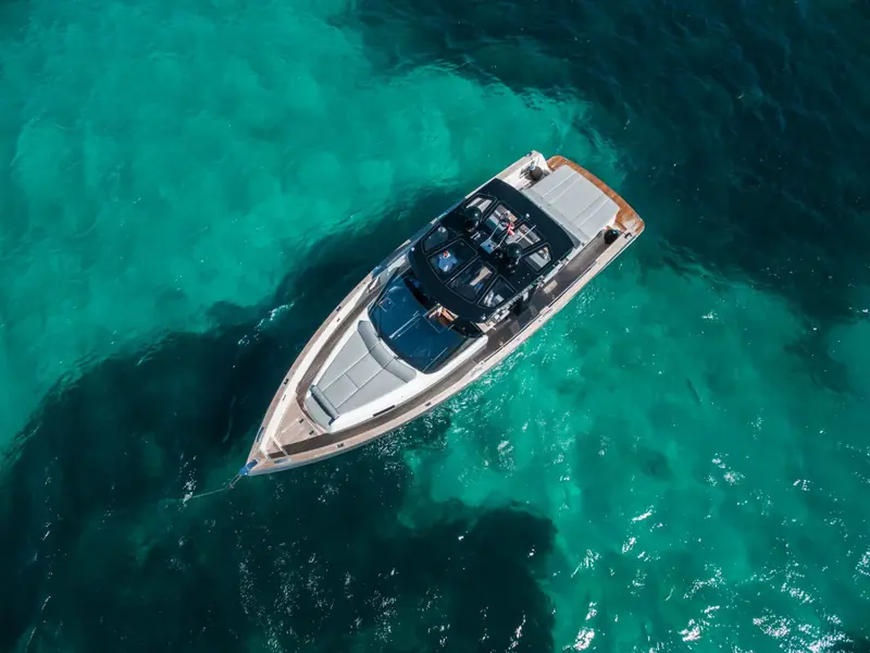 Aerial view of BOMBON, a Fjord 48 Open, anchored in clear turquoise water.