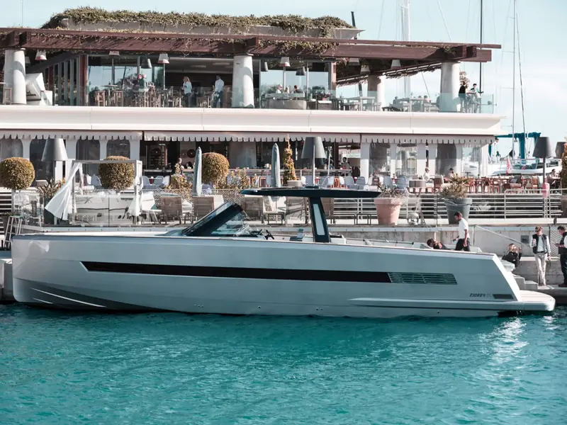 PETITCHET, a Fjord 52 Open motor yacht, moored in a marina next to a waterfront restaurant.