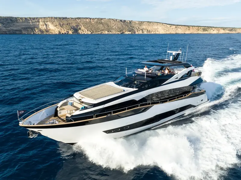 BLUE INFINITY ONE cruising at speed on the ocean with a rocky coastline in the background.