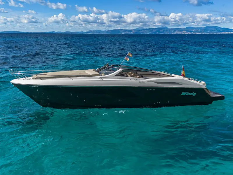 CUCA, a Windy 39 Camira motor yacht with a dark hull, anchored in turquoise water under a blue sky.
