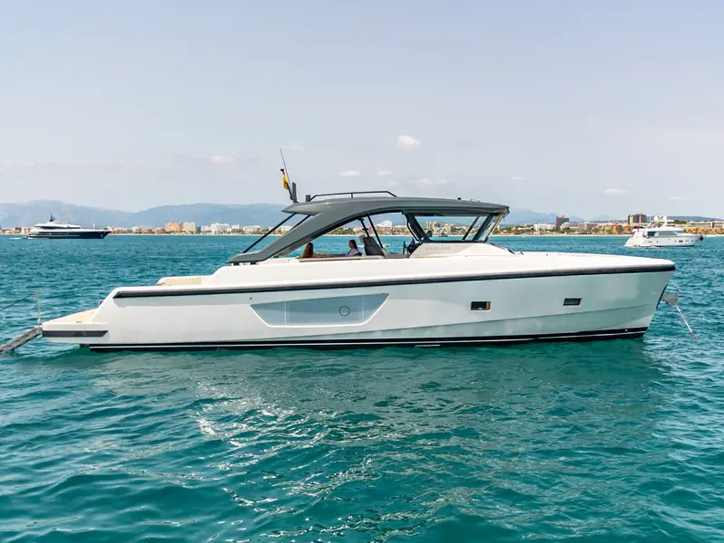 EXPERIENCE yacht, a Bluegame 54, anchored in calm turquoise water with a city skyline in the background.