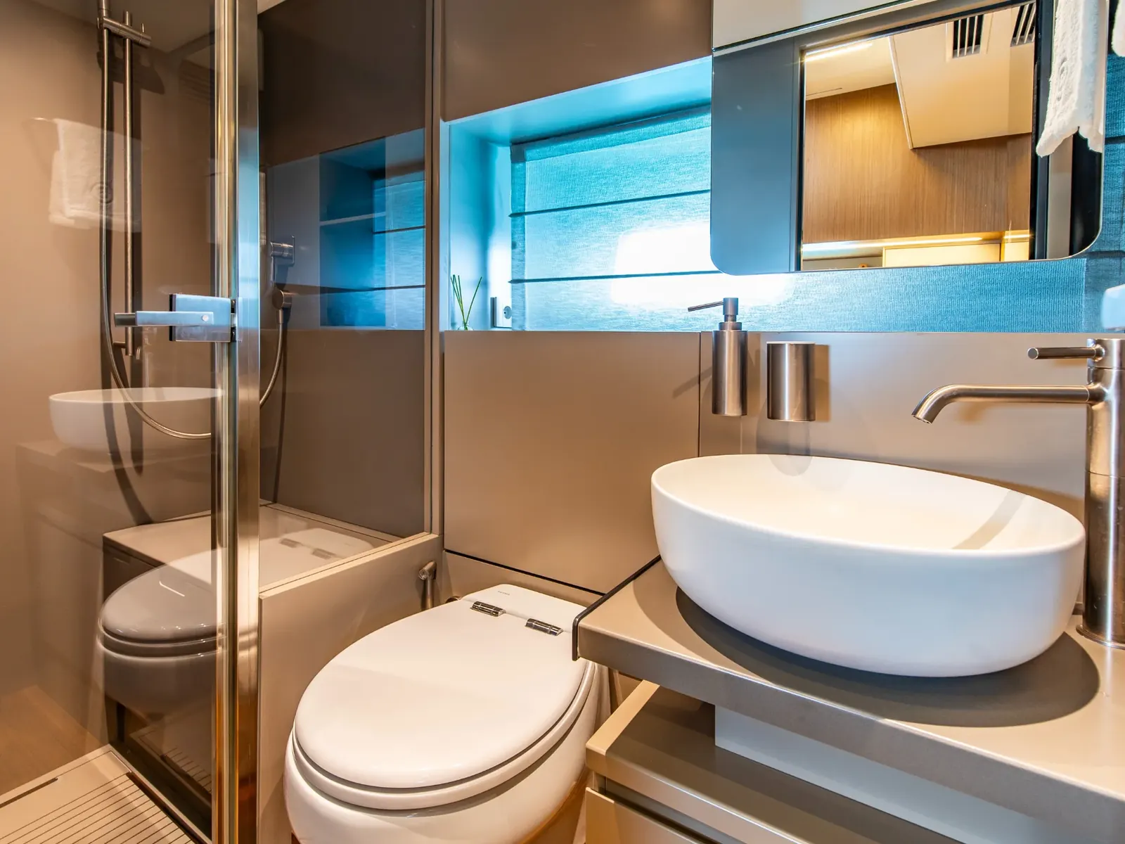 EXPERIENCE yacht bathroom featuring a white vessel sink, electric toilet, and glass-enclosed shower.