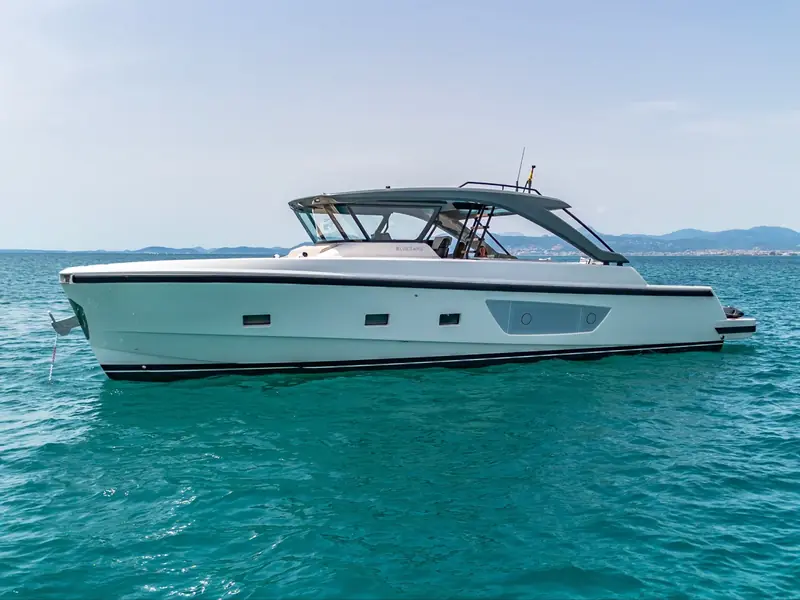 LIQUID SPIRIT, a Bluegame BG54 motor yacht, anchored on calm turquoise water with a distant shoreline.