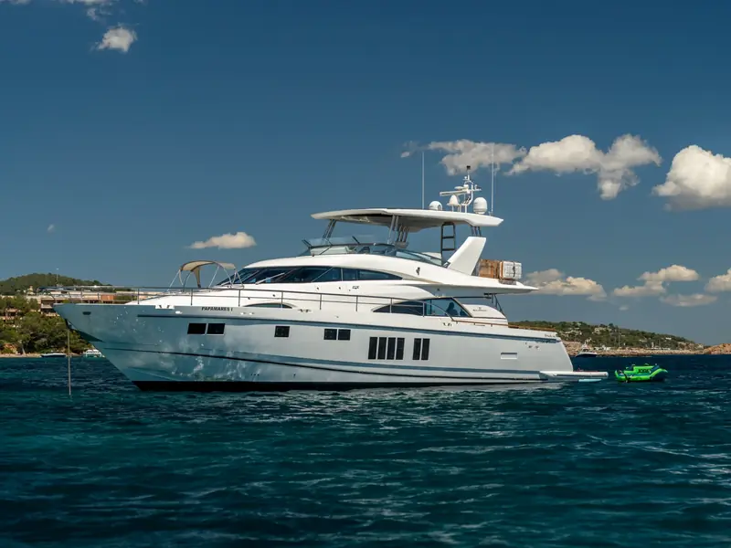 PAPAMARES motor yacht anchored in blue water with a green inflatable toy floating nearby.