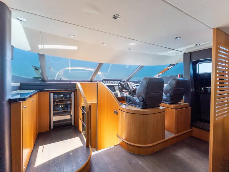 PAPAMARES helm station featuring two leather seats, wood cabinetry, and a wine cooler under the side counter.