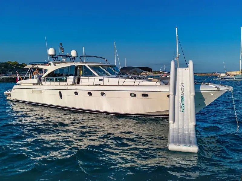 PARODIA yacht anchored with a large white inflatable slide deployed from the bow into the water.