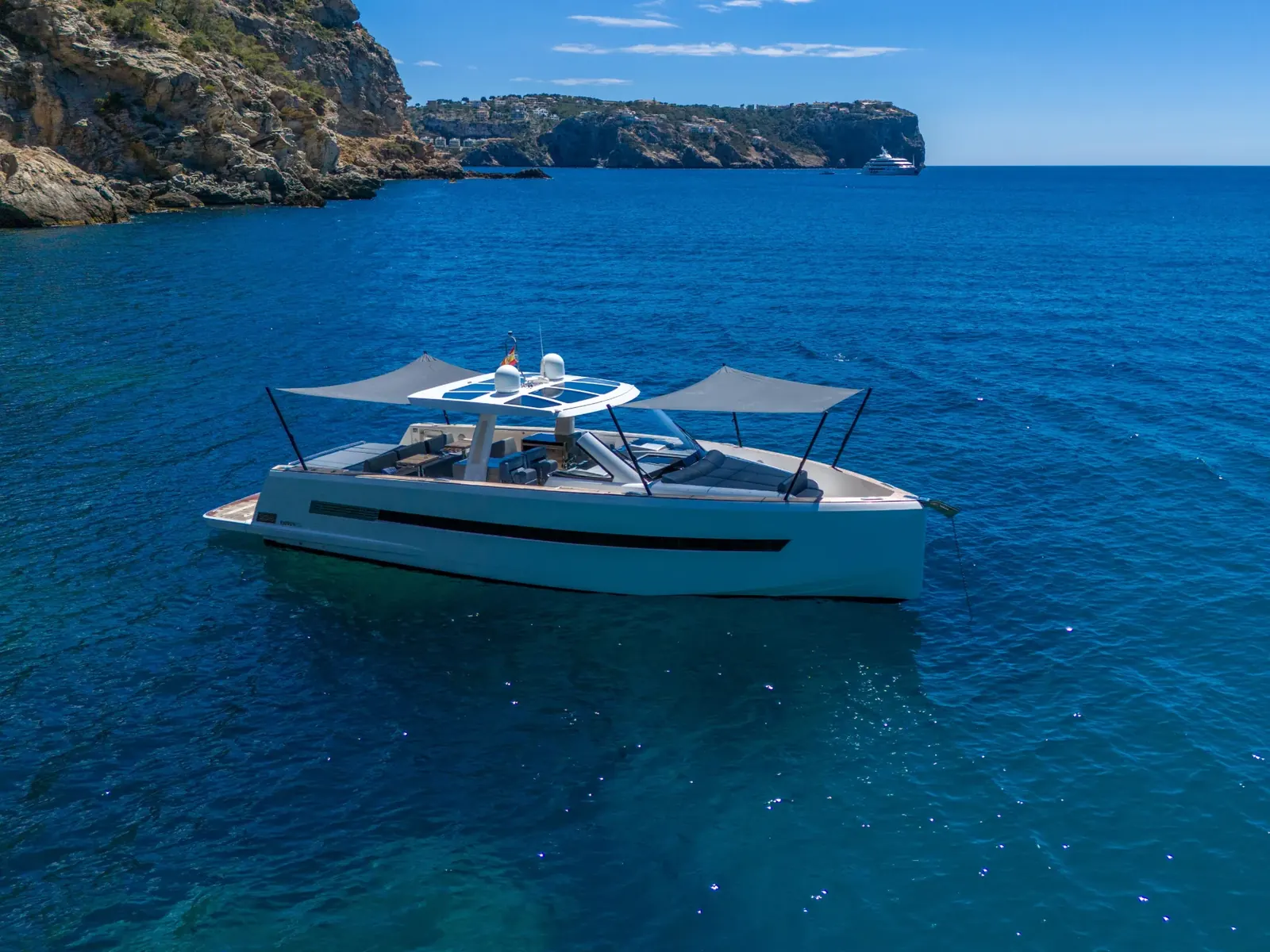 PETITCHET yacht anchored in a bay with sunshades deployed on the foredeck and aft deck.