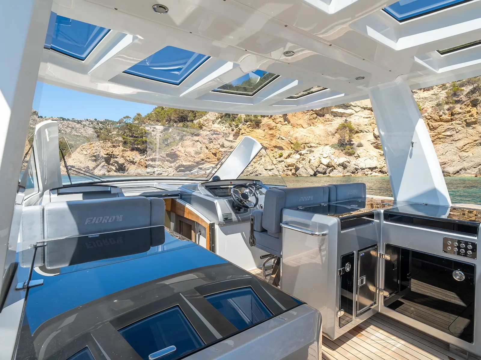 PETITCHET helm station and outdoor galley under a white hardtop with skylights.