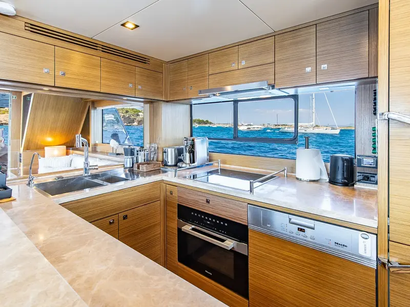 SALACIA yacht galley featuring Miele appliances, wooden cabinetry, and a view of the sea through a large window.