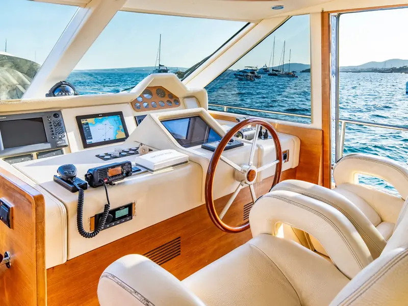 PARODIA helm station featuring a wooden steering wheel, Raymarine chartplotters, and Icom VHF radio.