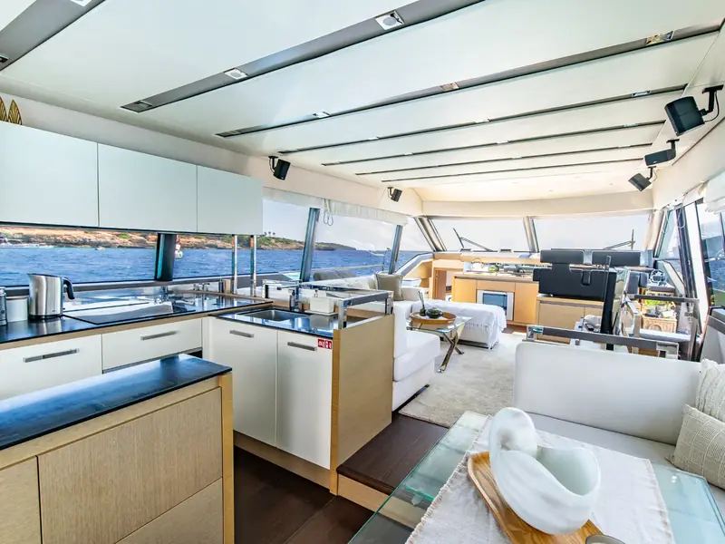 BLUE M yacht interior showing the galley area, salon seating, and helm station with large windows overlooking the sea.