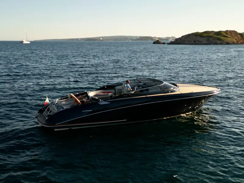 JAD & JULIA yacht, a dark-hulled Riva Rivarama, cruising on the sea with people on deck.