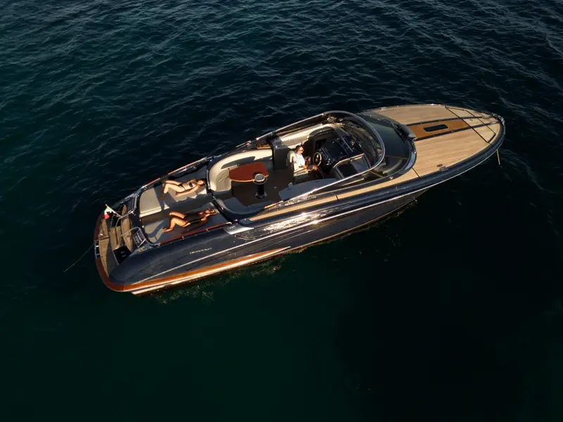 High-angle aerial view of JAD & JULIA, a Riva 44 Rivarama, with people on the aft sunpads in open water.