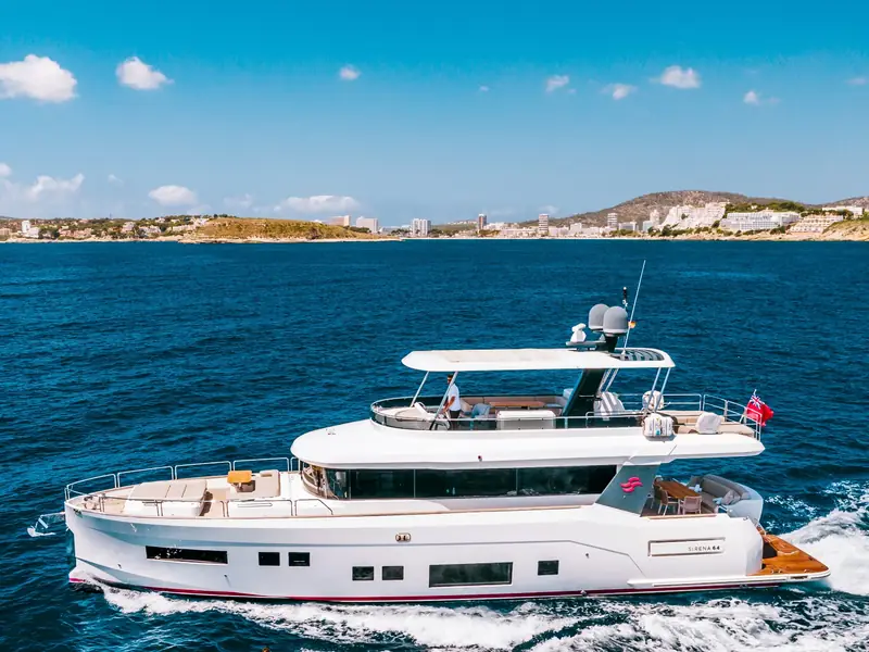 SALACIA, a Sirena 64 motor yacht, cruising at sea with a white hull and flybridge under a blue sky.
