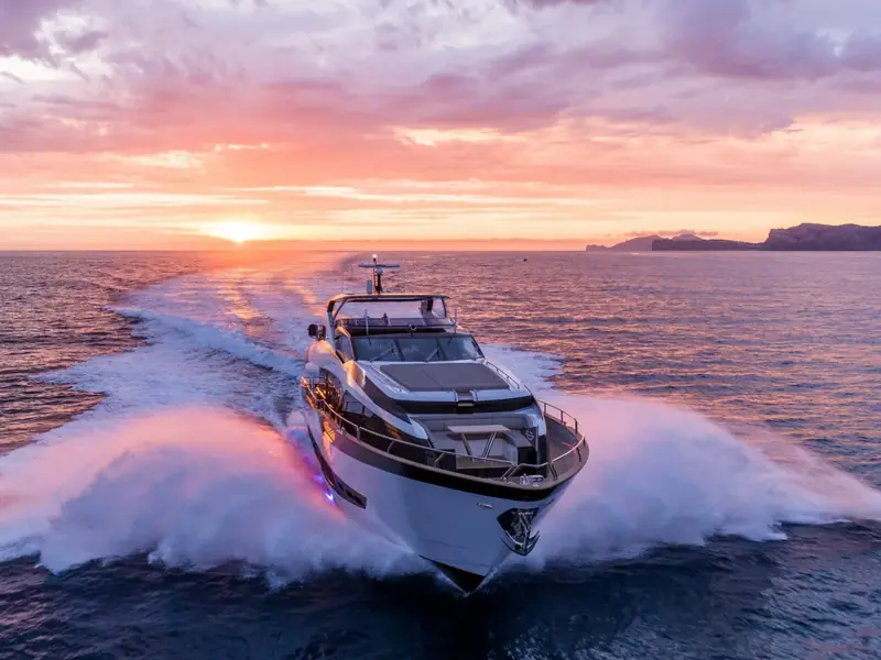 BLUE INFINITY ONE cruising at speed in the open sea during a pink sunset with white wake spray.