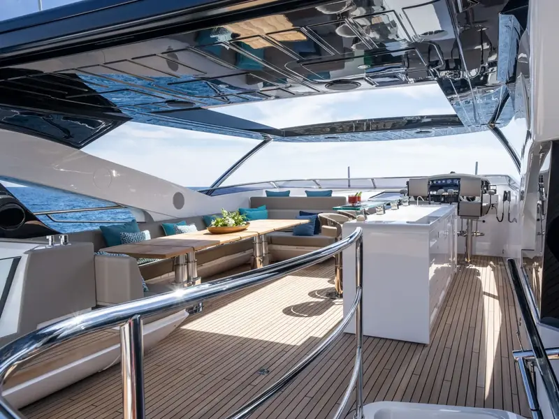BLUE INFINITY ONE flybridge featuring a teak deck, dining area, wet bar, and helm station under a hardtop.