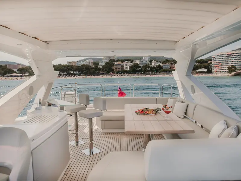 LADY M yacht flybridge with a dining table, bar stools, and a view of a coastal town.
