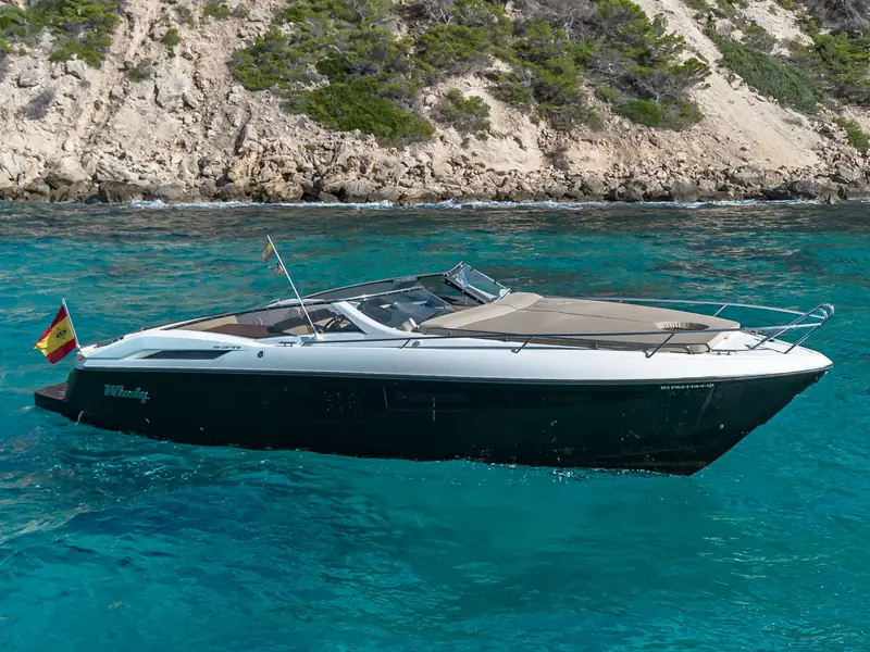 CUCA, a Windy 39 Camira motor yacht with a black hull and white superstructure, anchored in clear blue water.